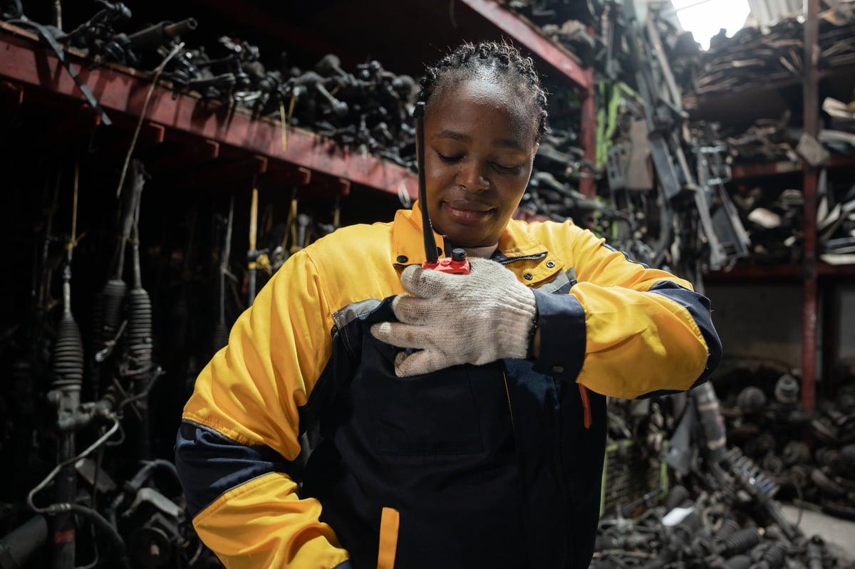 Portrait African American technician or engineer holding walkie talkie with auto part background