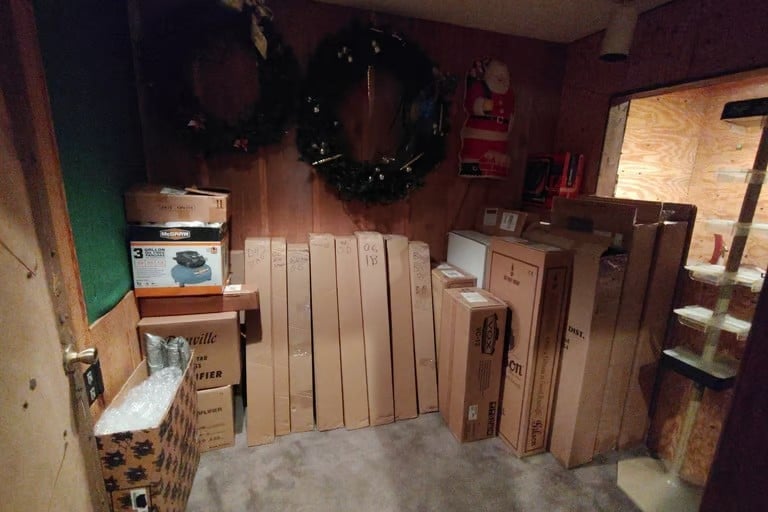 Storage room filled with wooden cabinet doors and panels, cardboard boxes, and holiday decorations on display