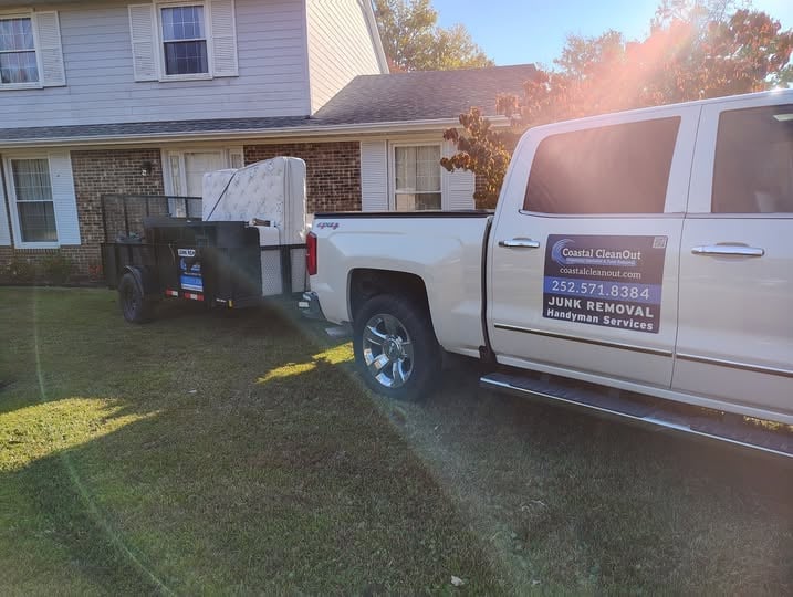White pickup truck and service van parked in residential driveway with junk removal equipment